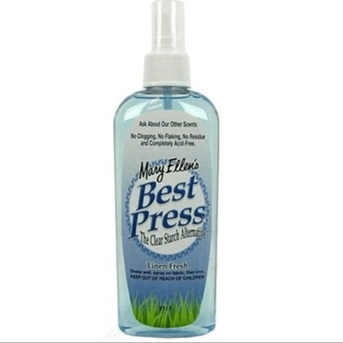 A spray bottle of Mary Ellen’s Best Press in Linen Fresh scent contains blue liquid in a for quilting, with product details on the front label.