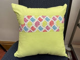 Yellow pillow with a colorful diamond pattern on a chair