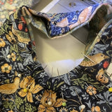 Fabric with bird pattern with lots of pins holding it in place. 