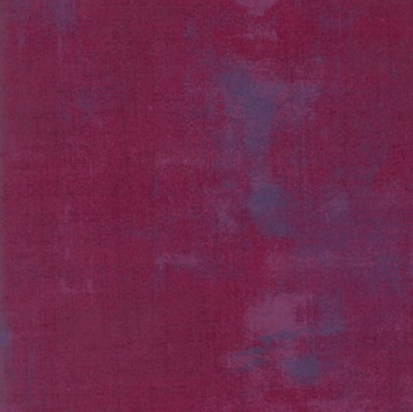 A textured look quilting fabric by Moda Grunge featuring a mix of dark magenta and subtle purple patches.