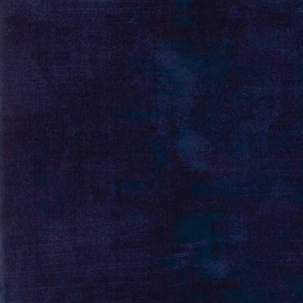 A square of dark purpley-blue quilting fabric with a distressed look of lighter blues as part of the design.