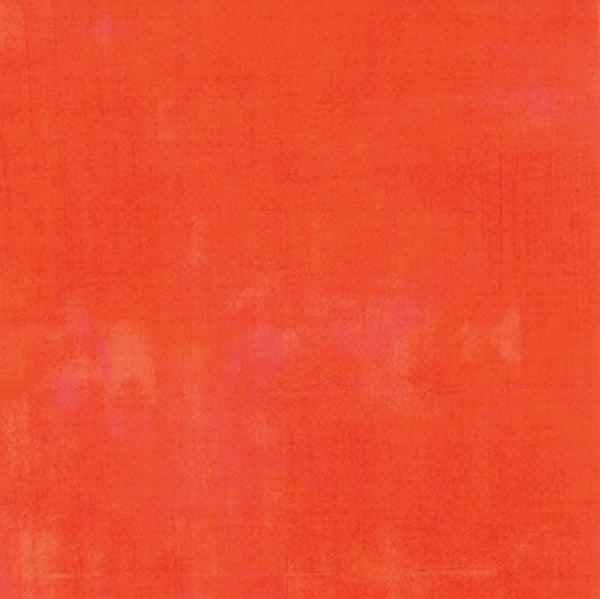 A vibrant orange textured background grunge quilting fabric by Moda with subtle shade variations and hints of pink.