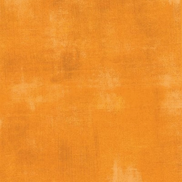 Moda Grunge features a textured orange background with subtle, uneven patches of lighter and darker shades, resembling a slightly distressed, painterly look on this quilting fabric.