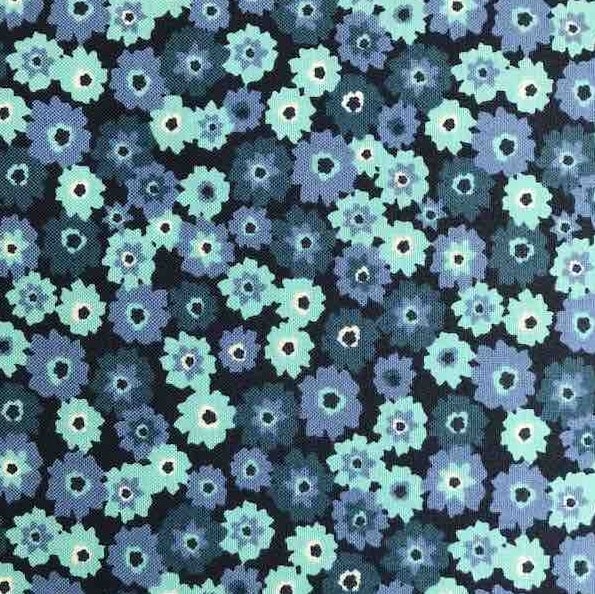 Moda’s quilting fabric features a dense scatter of small, pixelated blue and teal flowers with white centres on a dark background.