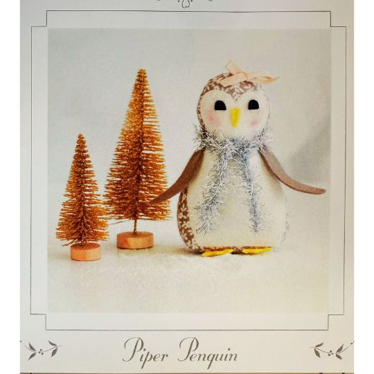 Stuffed penguin toy with decorative trees on a snowy background, featuring the brand 'Piper Penguin'.