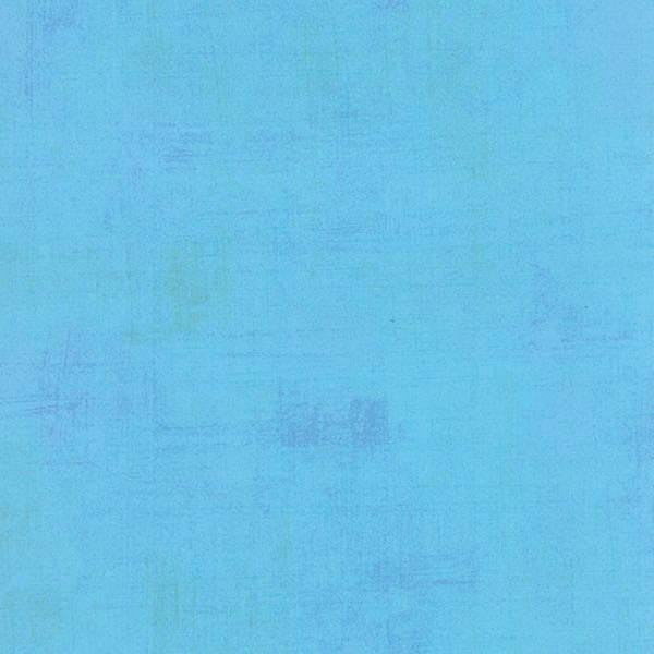 A textured blue quilting fabric in the Moda Grunge range, with subtle variations in shade and faint, uneven patterns throughout.